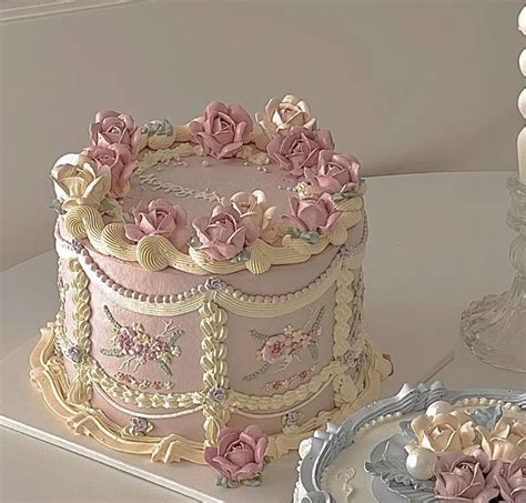 A Pink And Gold Decorated Cake Sitting On Top Of A Table Next To Two Plates