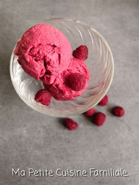 Two Scoops Of Raspberry Ice Cream In A Glass Bowl Next To Some Raspberries