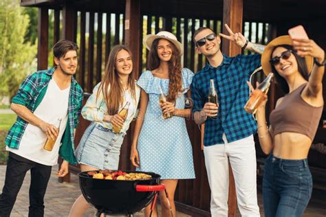 Jovens Amigos Fazendo Churrasco E Bebendo Bebidas Preparando Carne Na