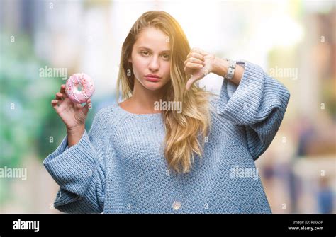 Junge hübsche blonde Frau isst Süßes Donut über isolierte Hintergrund mit Verärgerten Gesicht