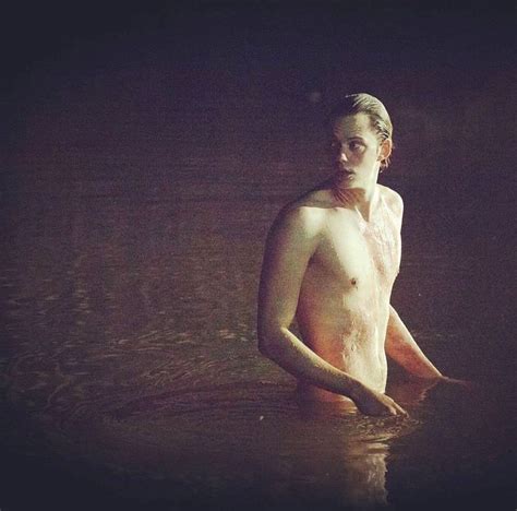 A Man Standing In The Water At Night With His Shirt Off And No Shirt On