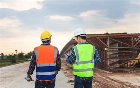 Engenheiro E Construtores Em Capacetes Discutindo No Canteiro De Obras