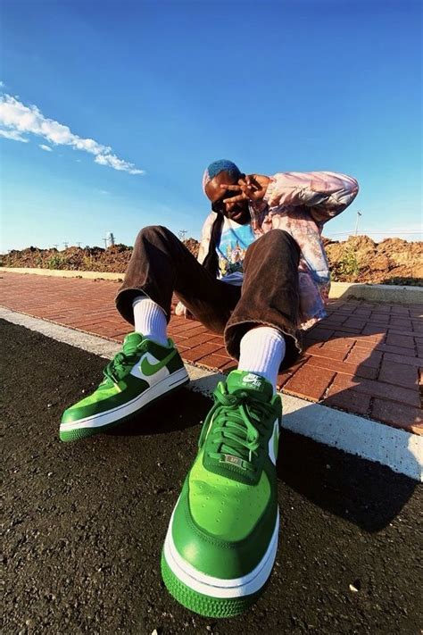 A Man Sitting On The Ground Next To A Green Shoe