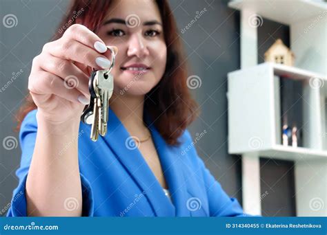A Curly Haired Brunette In A Blue Suit With A Smile On Her Face Confidently Holds Her Keys In