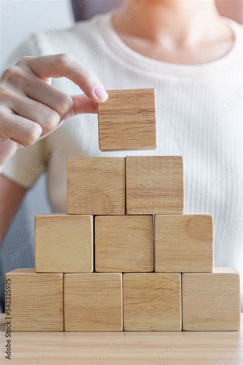 Woman Hand Placing Wood Block On The Building Leadership Business