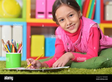 Cute little girl lying on floor and drawing Stock Photo - Alamy