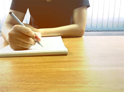 Premium Photo Midsection Of Man Writing In Book At Desk