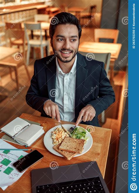 Indian Businessman Eating Lunch During Break After Work In Cafe And