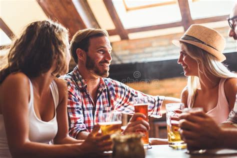 Pares Novos Que Bebem A Cerveja E Que Riem Junto Na Barra Imagem De