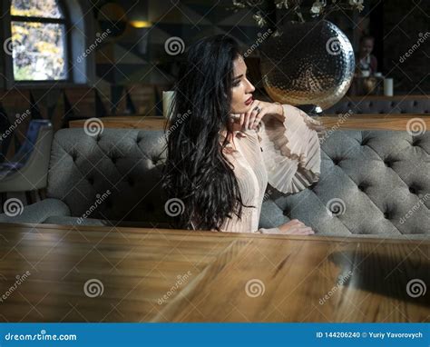 Beautiful Brunette Model Sitting On A Table In A Restaurant And Posing Photo Model On Photo