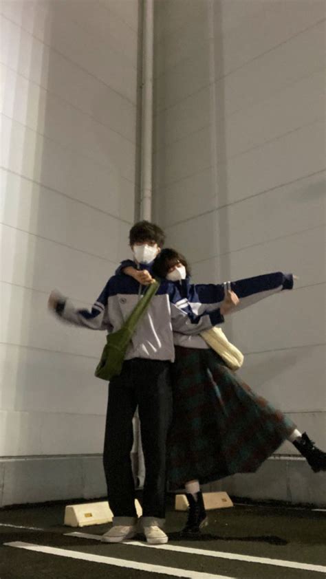 A Man And Woman Wearing Face Masks Standing In An Empty Parking Lot