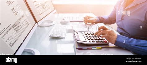 Bookkeeper Accountant Calculating Tax Invoice On Office Computer Stock