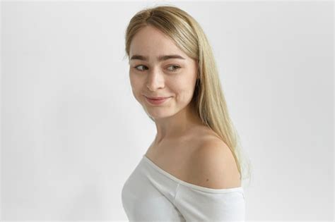 Geïsoleerde shot van gelukkige prachtige blonde vrouw met sproeten blote schouders draagt