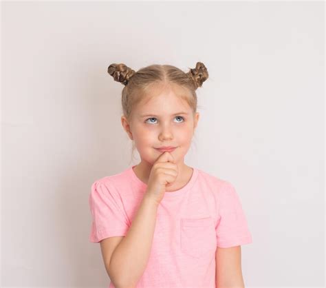 Niña pensativa mirando hacia arriba sobre fondo blanco Foto Premium