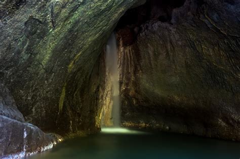 Premium Photo A Waterfall In A Cave With A Green Mossy Rock Wall