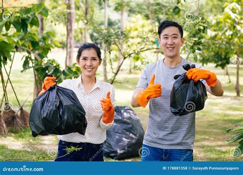 Young Asian Male And Female Couple Volunteers With Gloves Giving Thumbs