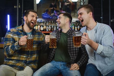 Tres J Venes Con Ropa Informal Sonr En Y Tocan Vasos De Cerveza Juntos