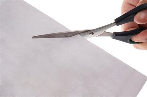 Premium Photo | Cropped hand cutting paper with scissors against white ...