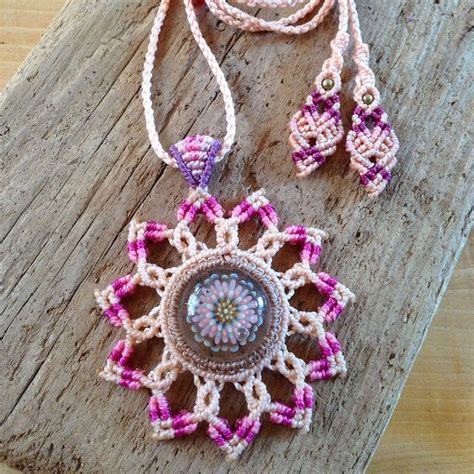 A Crocheted Necklace And Earring Sitting On Top Of A Piece Of Wood