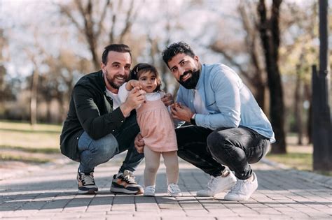 Retrato de una pareja gay masculina disfrutando con su hija en el parque concepto de adopción
