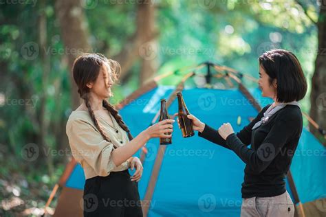 Young women cheer and drink beverage front of camping tent 21043157 ...