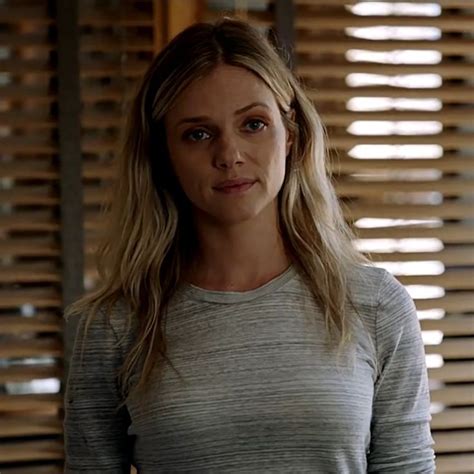 A Woman Standing In Front Of Blinds Looking At The Camera With An Angry