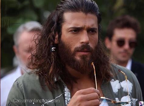 A Man With Long Hair And Beard Holding A Straw In His Hand While