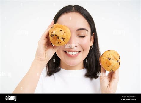 Close Up Portrait Of Funny Asian Girl Holds Cupcakes Near Face Makes