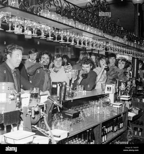 A Group Of Mainly Young Men Standing Around A Bar In An English Pub