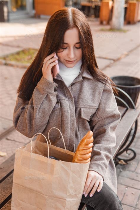 A Stylish Brunette Woman Walks Around The Autumn City The Brunette Is Sitting On A Bench