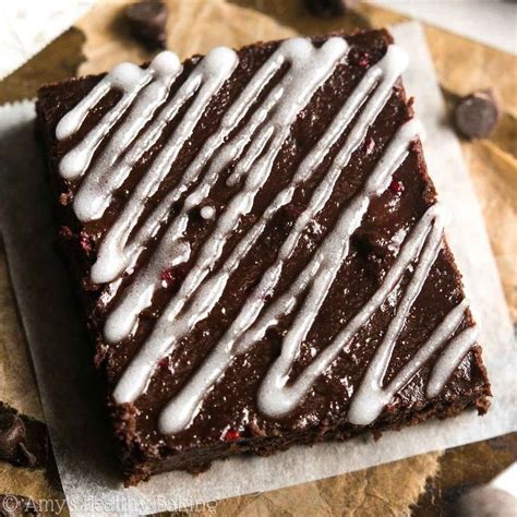 A Piece Of Brownie With White Icing Sitting On Top Of Paper Next To