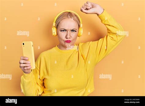 Jeune femme blonde dansant en portant des écouteurs sceptique et nerveux frowning bouleversé à