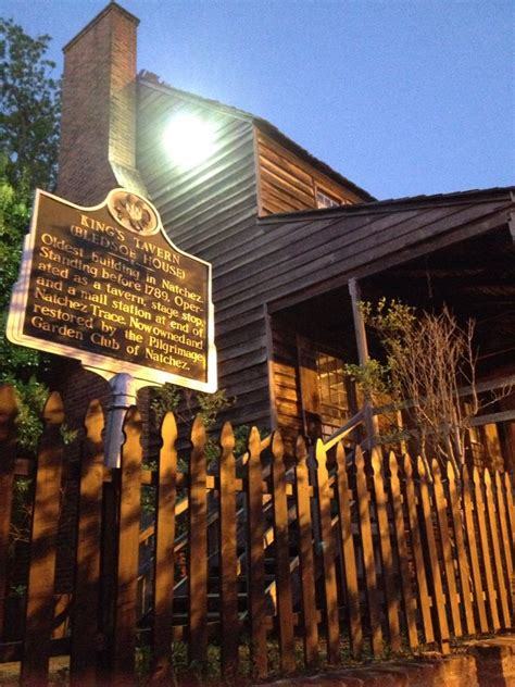 A Wooden House With A Sign On The Front And Side Of It At Night Time