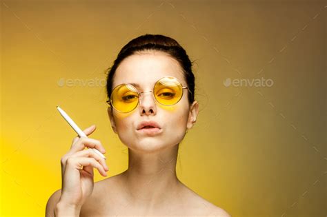 Brunette In Yellow Glasses Naked Shoulders Cigarette In Hands Emotions Yellow Background Stock