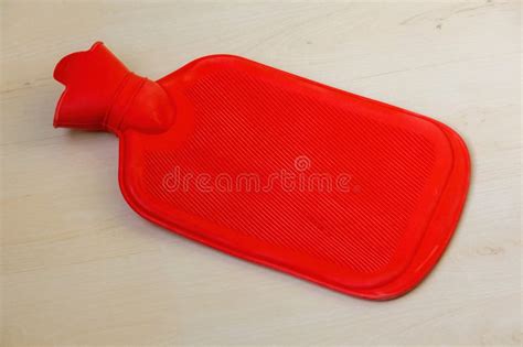 A Red Hot Water Bottle Rests On A Wooden Surface This Rubber Hot Water Bag Is Designed For