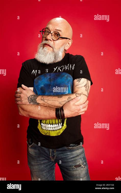 Portrait Of Bearded Mature Bald Man In Glasses And Casual Stylish Clothes With Tattoos Posing
