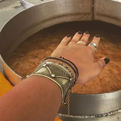 A Woman S Hand Resting On The Bottom Of A Metal Pot Filled With Brown