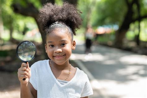 Una Ni A Afroamericana Sonriente Sostiene Una Lupa Para Explorar Y