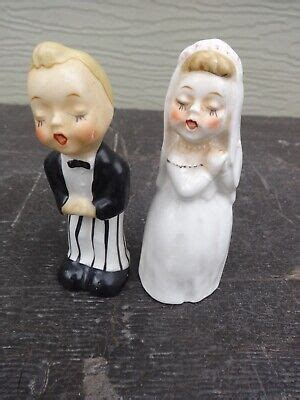 Two Wedding Figurines Are Standing Next To Each Other On A Wooden Table