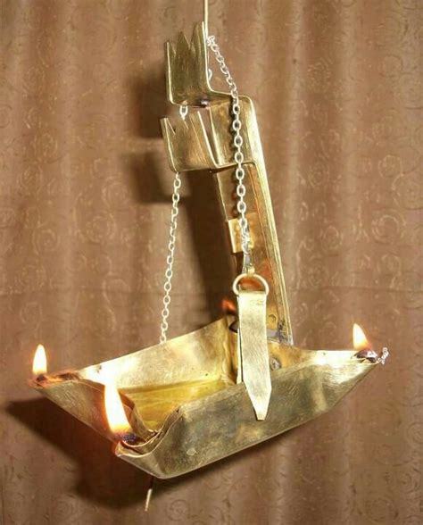 A Candle Is Lit In Front Of A Boat Shaped Chandelier With Chains