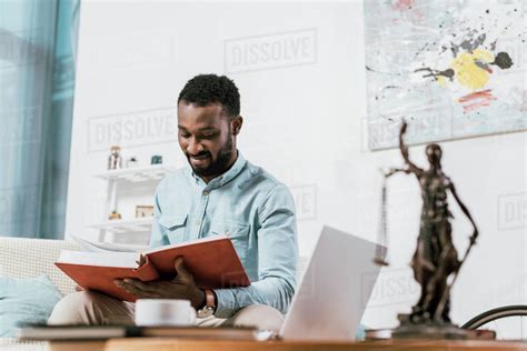 Selective Focus Of African American Man Reading Book In Living Room