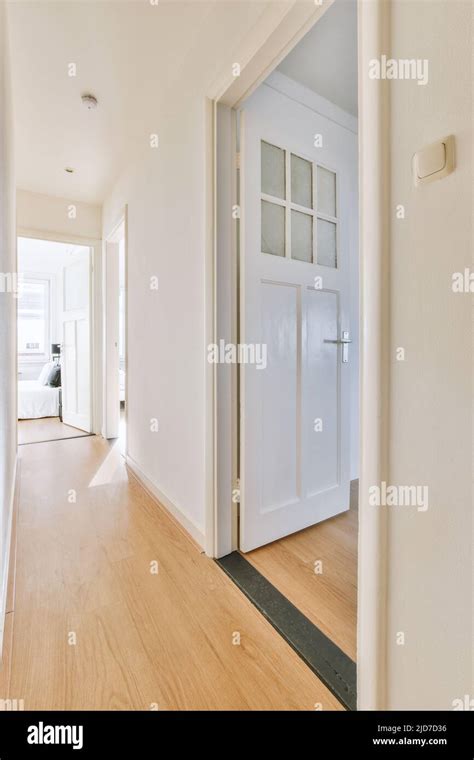 Light Narrow Corridor With Several Doors In White Walls With Wooden