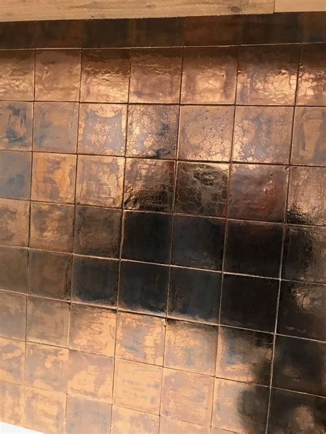 A Close Up Of A Tiled Wall In A Bathroom With Brown And Black Tiles On It