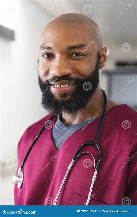 Portrait Of Happy African American Male Doctor Wearing Red Scrubs In