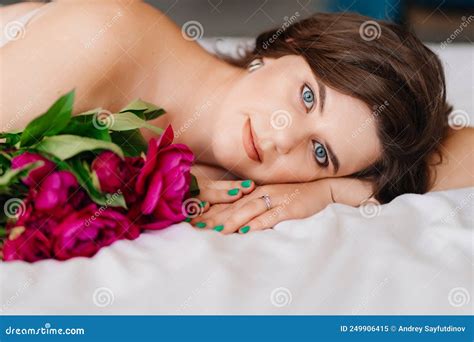 A Gentle Brunette Woman In Bed With A Bouquet Of Peonies Morning Of Holiday Stock Image