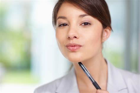 Cute Young Woman Holding A Pen At Her Chin Stock Photo Download Image