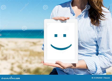 Woman Displaying Digital Tablet With Smiley Face At Beach Stock Photo