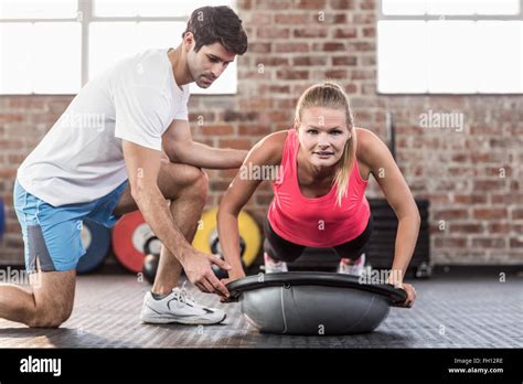 Trainer Assisting Woman With Push Ups At Gym Stock Photo Alamy