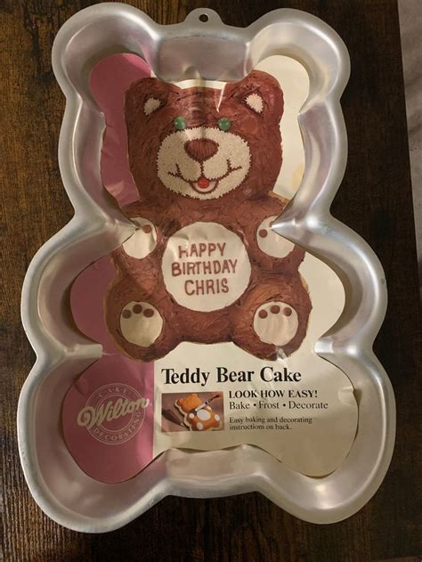 A Teddy Bear Cake In A Plastic Tray On A Wooden Table With An Advertise