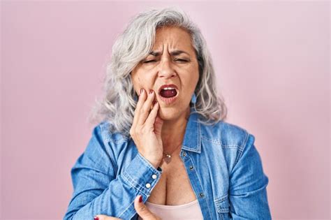 Mujer De Mediana Edad Con Cabello Gris Sobre Fondo Rosa Tocando La Boca